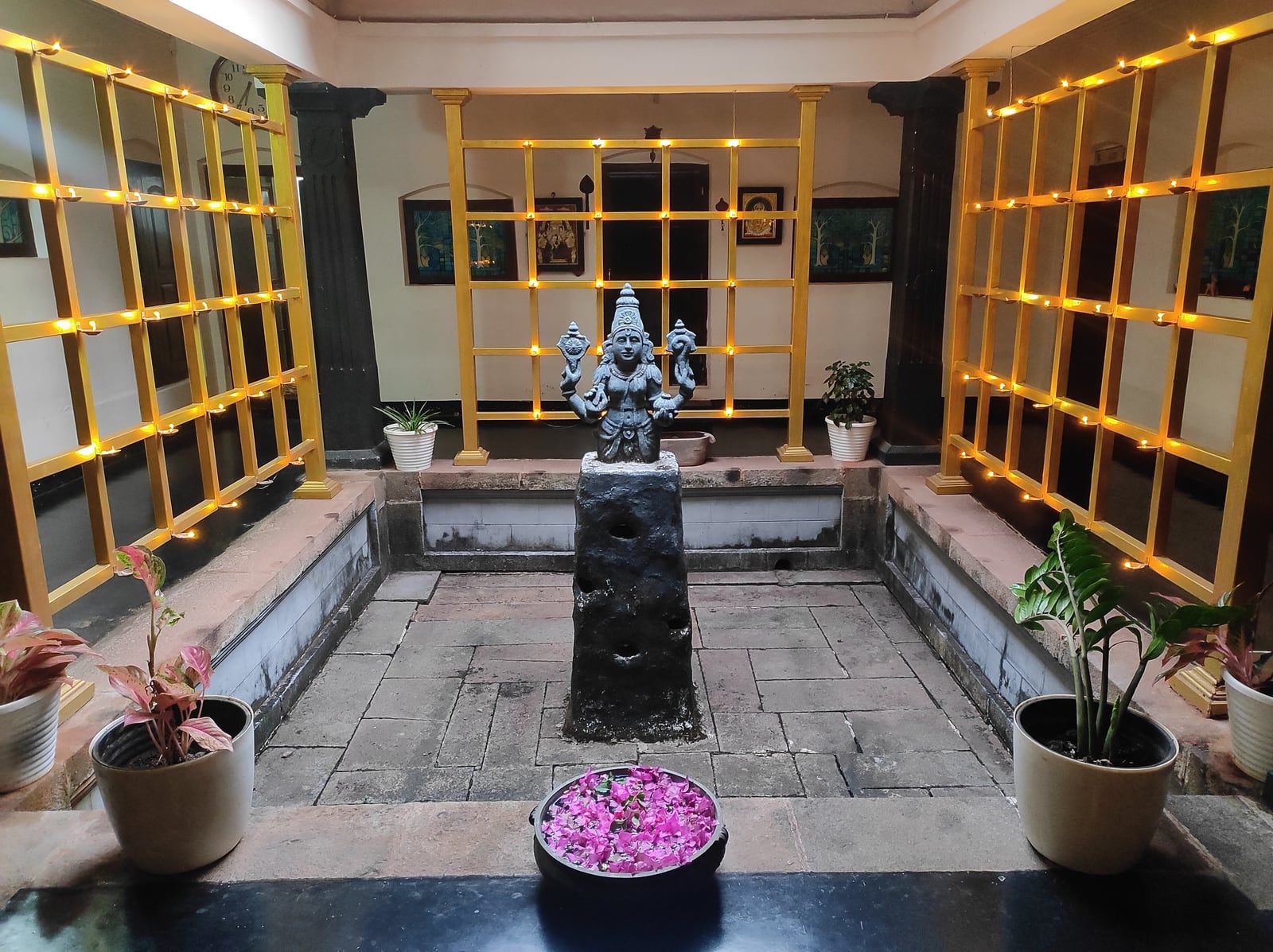 A courtyard with oil lamps and a statue of a deity