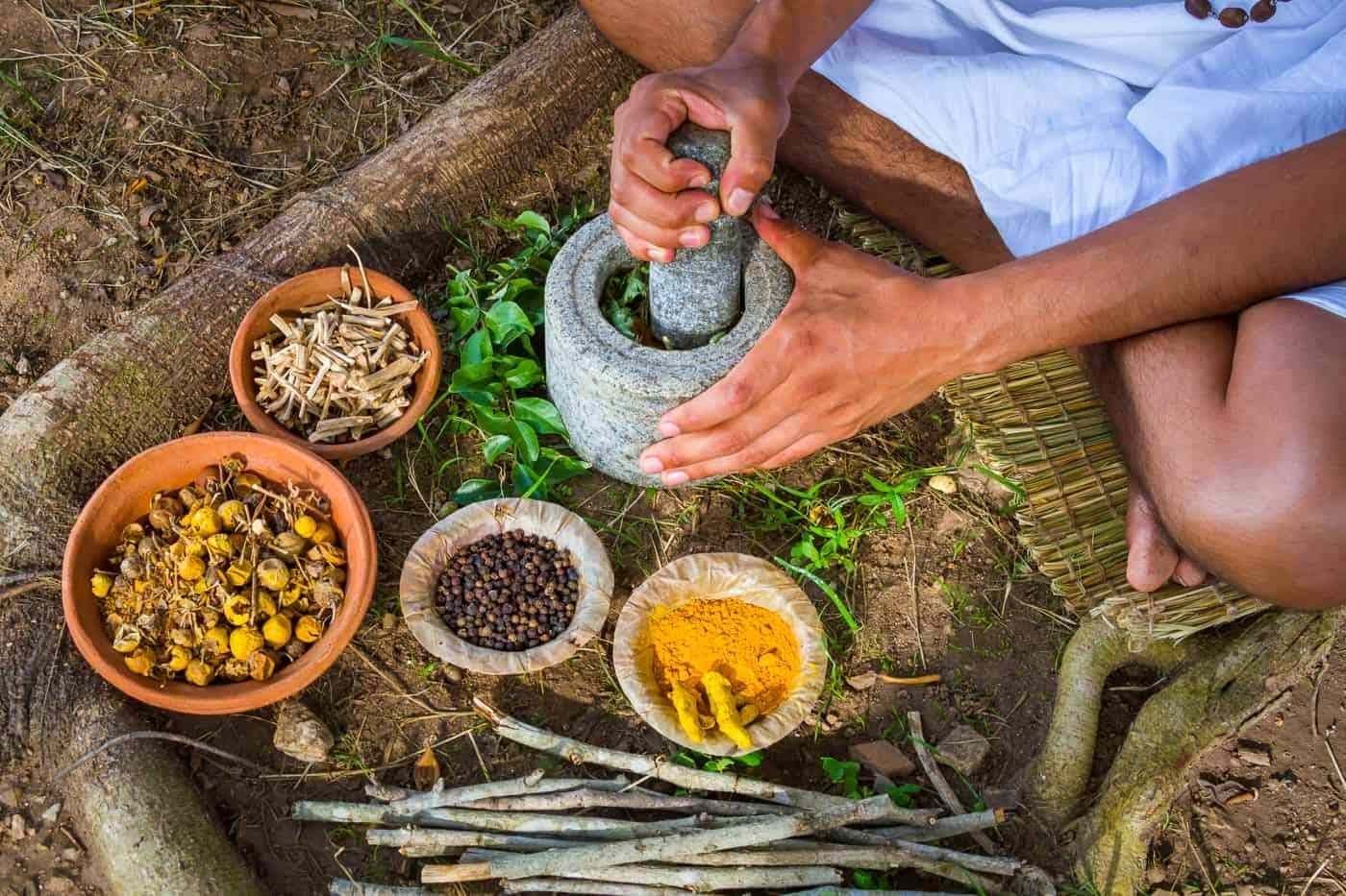 Grinding herbs with a pestle to make a medicated oil