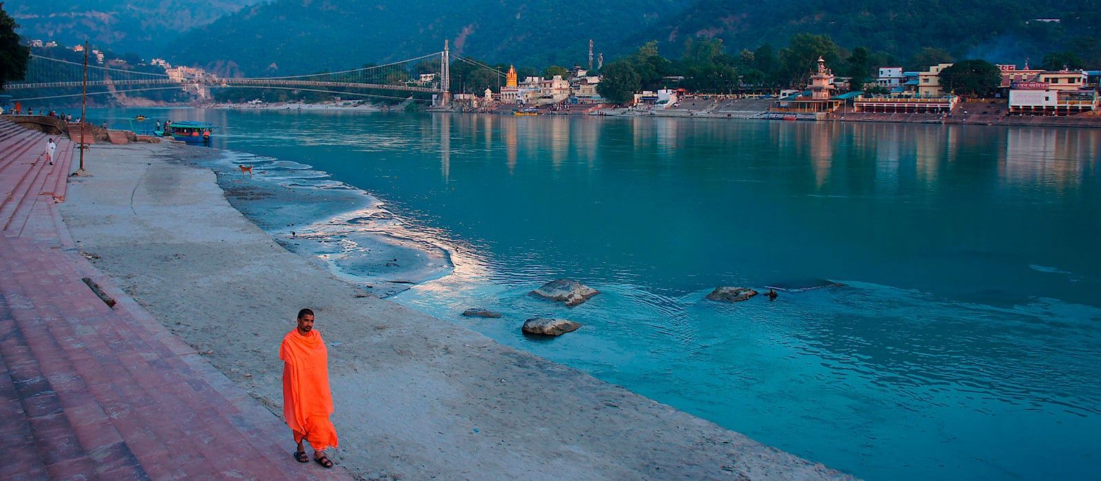 The bank of the Ganga in Rishikesh, with a bridge and the Himalayan foothills in the distance